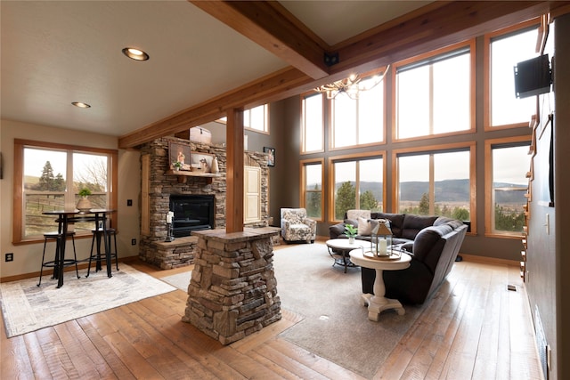 living room with beam ceiling, a fireplace, light wood-type flooring, and a healthy amount of sunlight