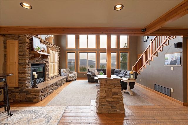 living room featuring hardwood / wood-style flooring, beamed ceiling, and a fireplace