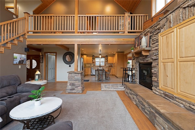 living room with light hardwood / wood-style flooring, a stone fireplace, and high vaulted ceiling