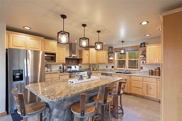 kitchen with wall chimney exhaust hood, sink, a breakfast bar, a center island, and appliances with stainless steel finishes