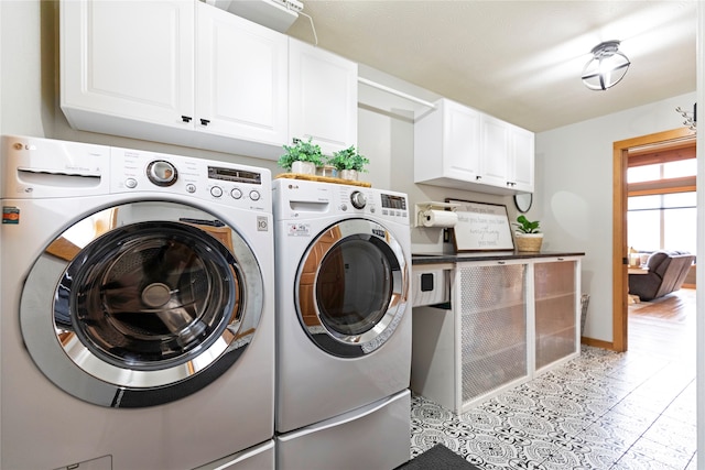 clothes washing area featuring cabinets and washer and clothes dryer