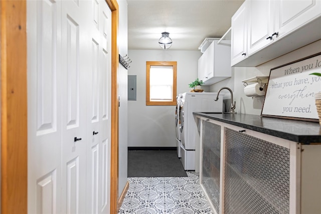 washroom featuring electric panel, independent washer and dryer, and cabinets