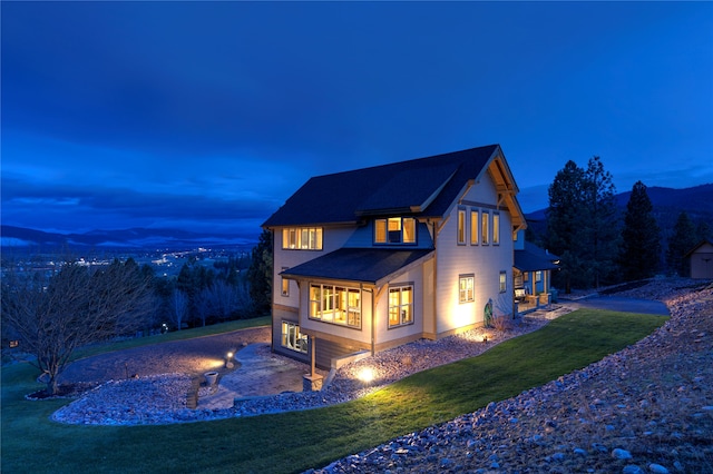 back house at dusk with a lawn