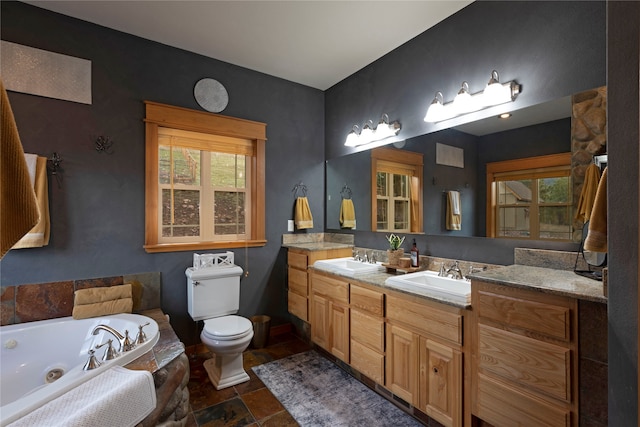 bathroom featuring vanity, a tub to relax in, and toilet