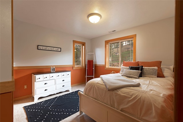 bedroom featuring a textured ceiling and light colored carpet