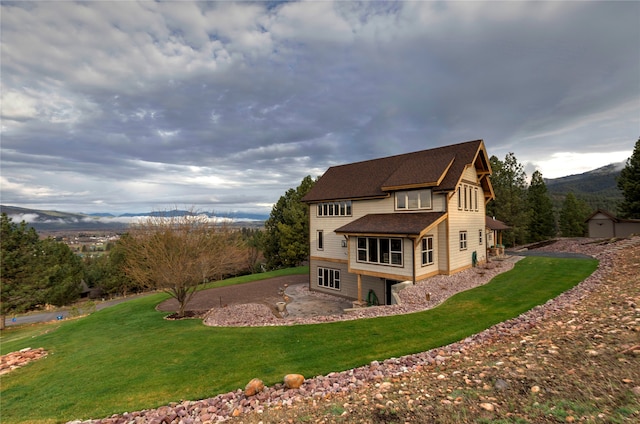 back of property featuring a mountain view and a lawn