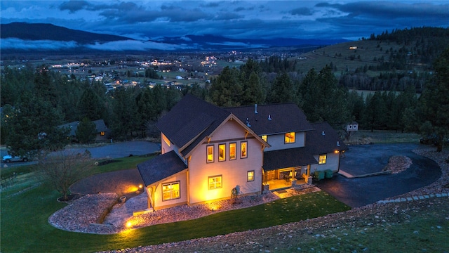 back house at dusk with a mountain view and a yard