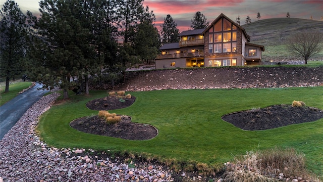 view of front of home with a mountain view, a yard, and a balcony