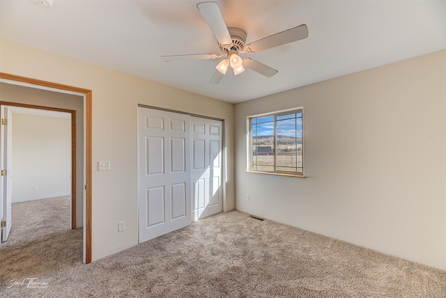 unfurnished bedroom featuring light carpet, a closet, and ceiling fan