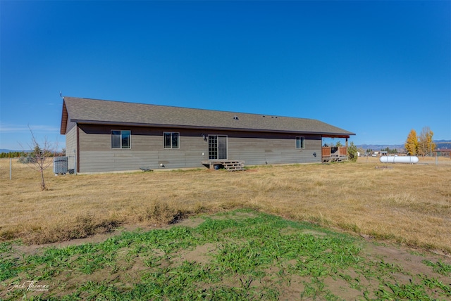 rear view of property featuring a yard and central air condition unit