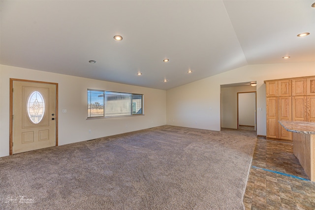 unfurnished living room featuring lofted ceiling and dark colored carpet