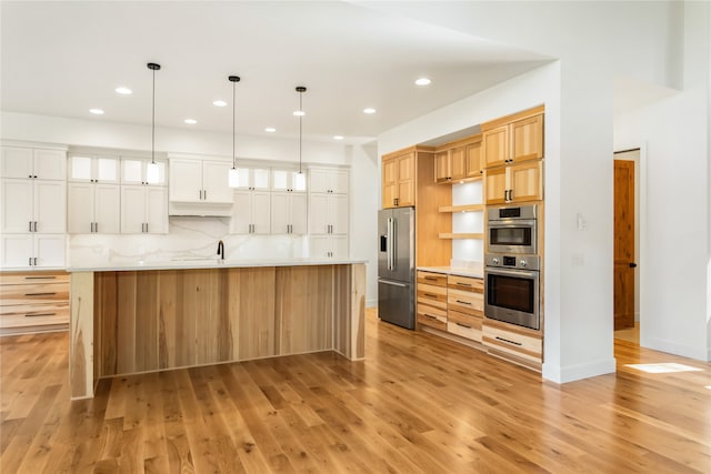 kitchen with a large island, white cabinets, tasteful backsplash, appliances with stainless steel finishes, and light hardwood / wood-style flooring