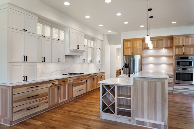 kitchen with light hardwood / wood-style floors, white cabinetry, stainless steel appliances, and an island with sink