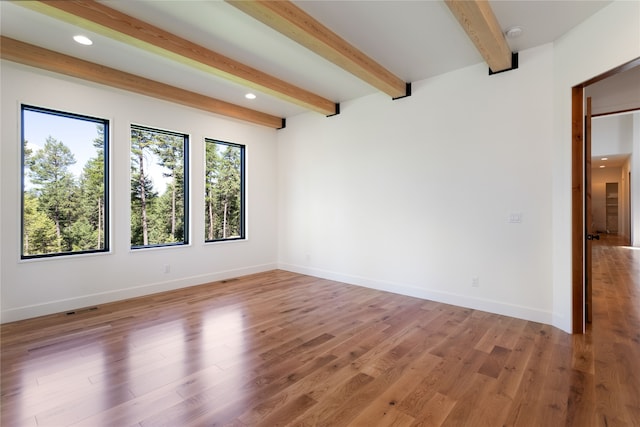 spare room with beam ceiling and hardwood / wood-style flooring