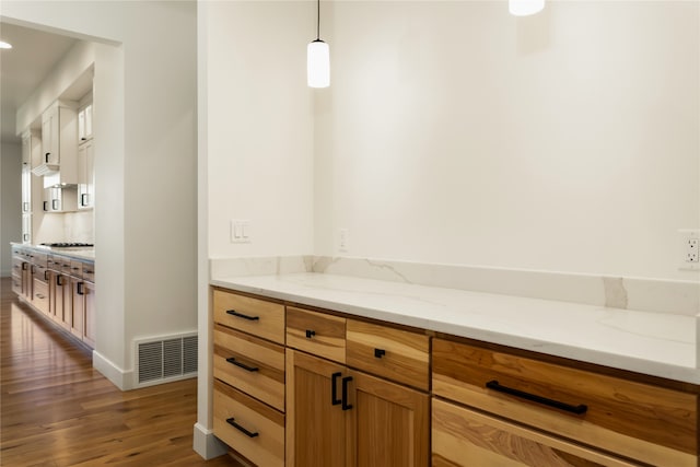 interior space featuring hardwood / wood-style floors, light stone countertops, hanging light fixtures, and gas cooktop