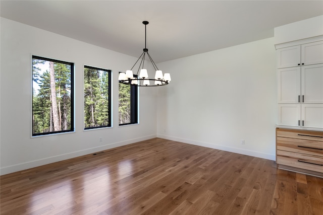 unfurnished dining area with an inviting chandelier and dark hardwood / wood-style floors