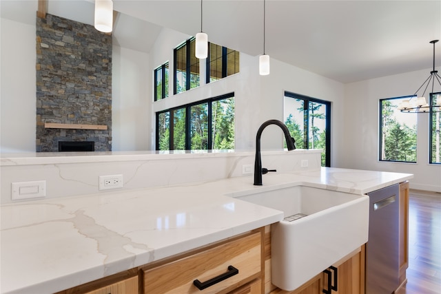 kitchen with stainless steel dishwasher, light stone counters, and pendant lighting