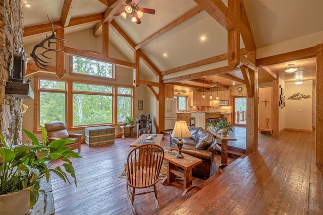 living room with a stone fireplace, hardwood / wood-style flooring, beam ceiling, high vaulted ceiling, and ceiling fan