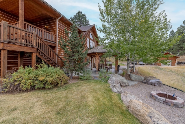 view of yard featuring a deck, a patio, and a fire pit