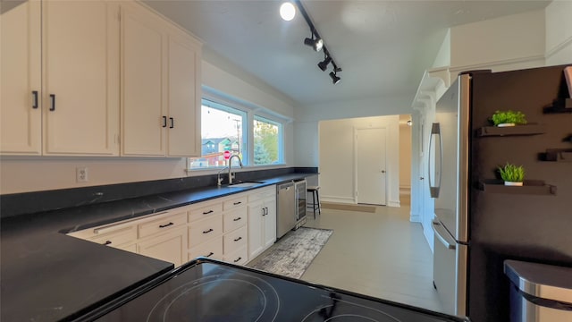 kitchen featuring appliances with stainless steel finishes, white cabinetry, sink, and rail lighting