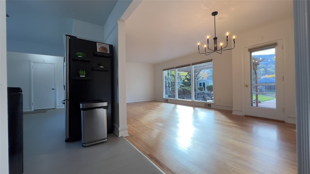 unfurnished dining area featuring a notable chandelier and light wood-type flooring