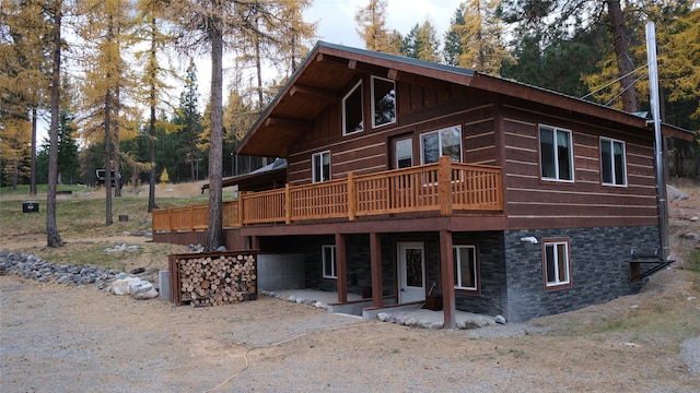 back of property featuring a wooden deck and a patio