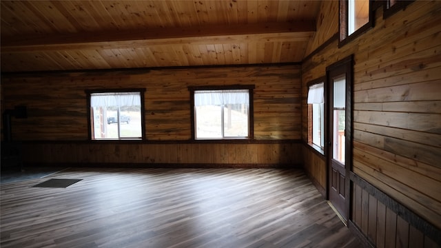 spare room featuring beamed ceiling, wood ceiling, dark hardwood / wood-style floors, and wood walls