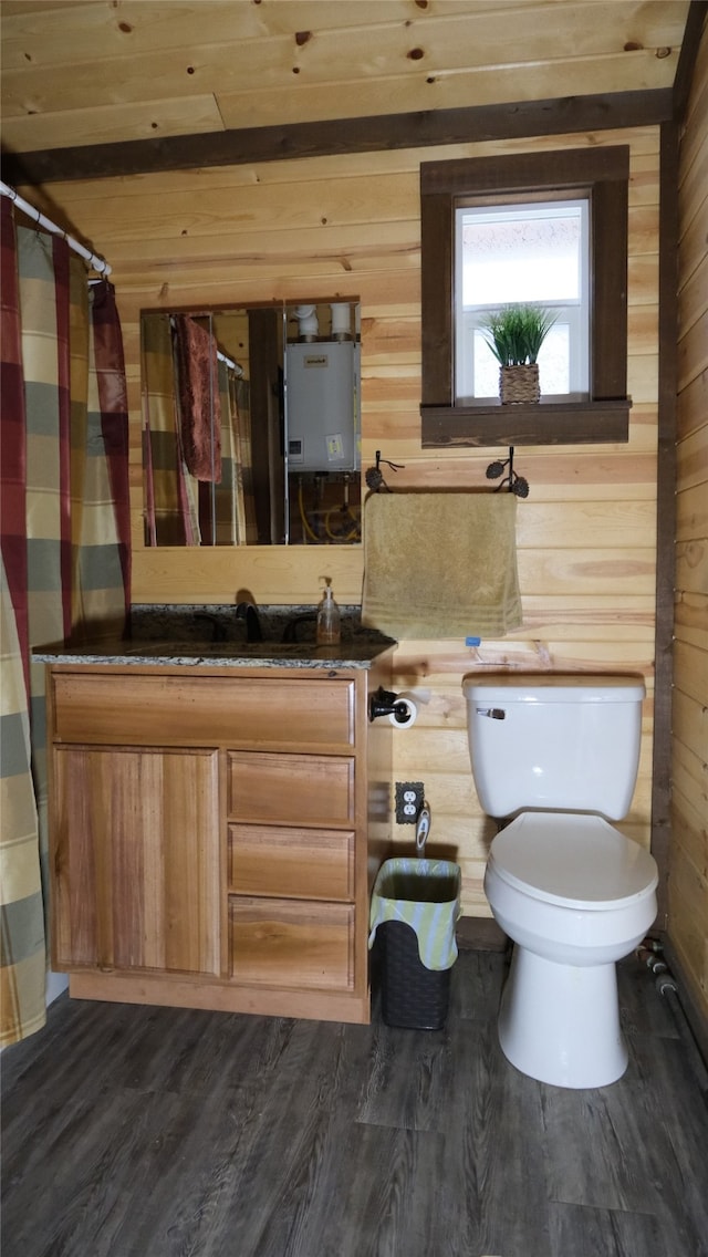 bathroom featuring wood-type flooring, toilet, wood walls, vanity, and tankless water heater