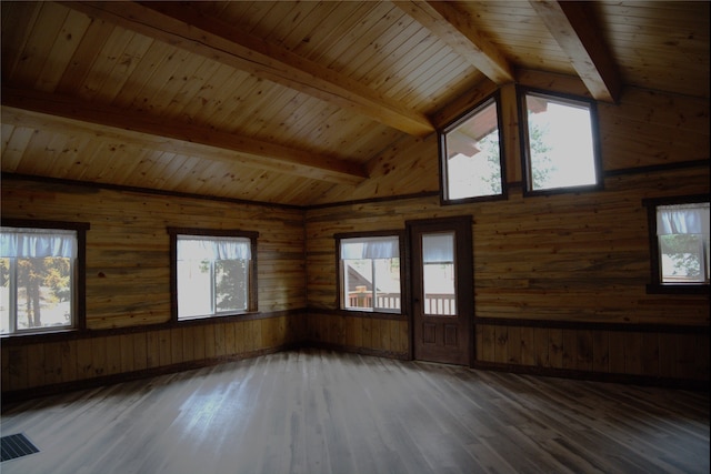 spare room featuring vaulted ceiling with beams, plenty of natural light, and dark hardwood / wood-style flooring