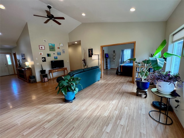 living room with light hardwood / wood-style floors, high vaulted ceiling, and ceiling fan