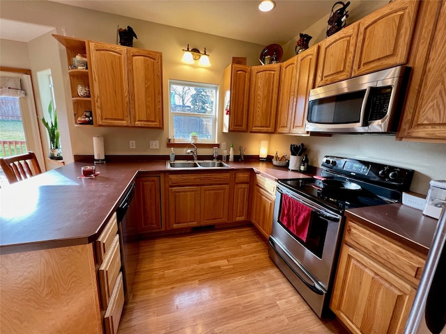 kitchen featuring sink, kitchen peninsula, stainless steel appliances, and light wood-type flooring