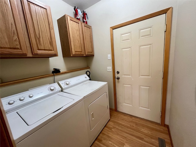 laundry room with independent washer and dryer, light wood-type flooring, and cabinets