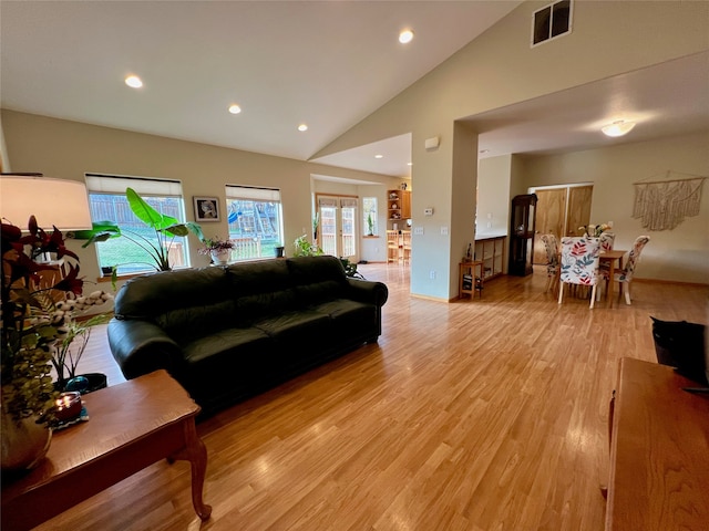 living room with light hardwood / wood-style flooring and high vaulted ceiling