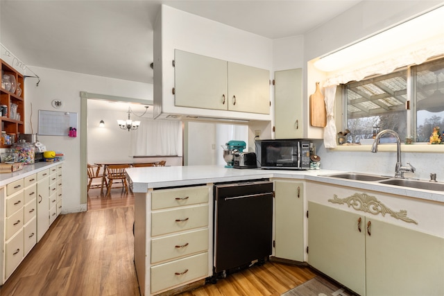 kitchen with black appliances, sink, kitchen peninsula, hanging light fixtures, and hardwood / wood-style flooring