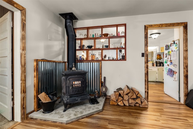 interior details with a wood stove, wood-type flooring, and white refrigerator