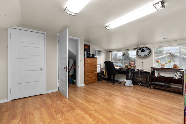 office with light hardwood / wood-style flooring, an AC wall unit, and vaulted ceiling