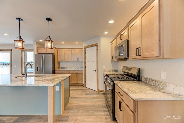 kitchen featuring hanging light fixtures, light wood-type flooring, an island with sink, stainless steel appliances, and ceiling fan with notable chandelier