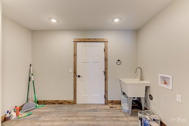 clothes washing area with washer hookup and light wood-type flooring