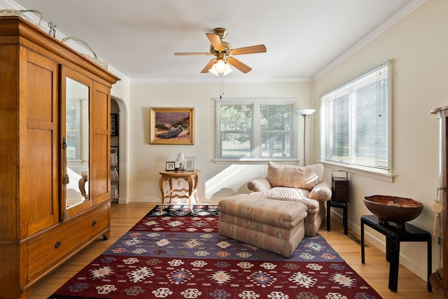 living area featuring crown molding, light hardwood / wood-style flooring, and ceiling fan