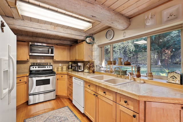 kitchen featuring appliances with stainless steel finishes, sink, tile countertops, light hardwood / wood-style floors, and beamed ceiling