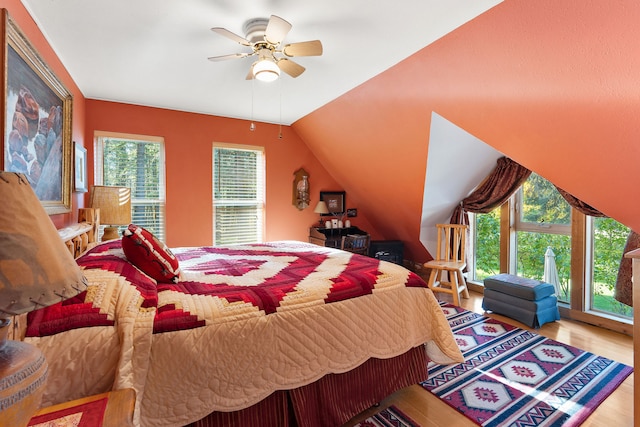 bedroom featuring vaulted ceiling, multiple windows, light wood-type flooring, and ceiling fan