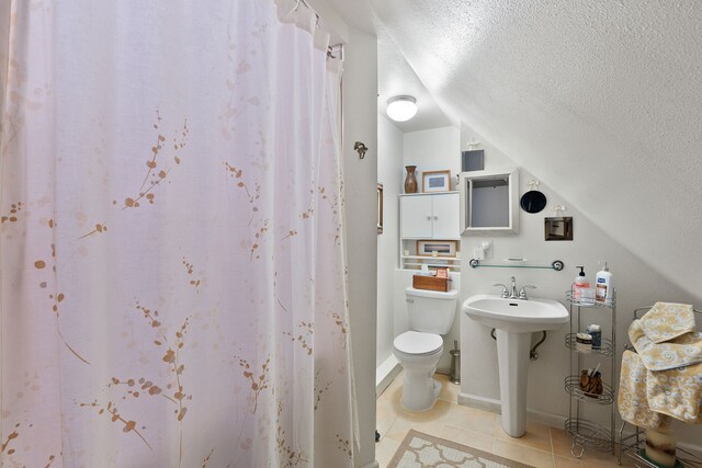 bathroom with a textured ceiling, vaulted ceiling, toilet, a shower with curtain, and tile patterned floors