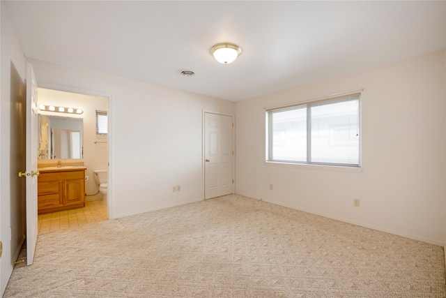 unfurnished bedroom featuring light carpet, a closet, and connected bathroom