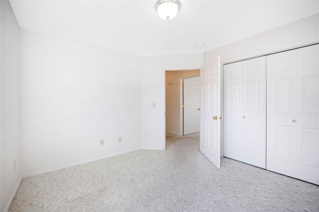 unfurnished bedroom featuring a closet and light colored carpet