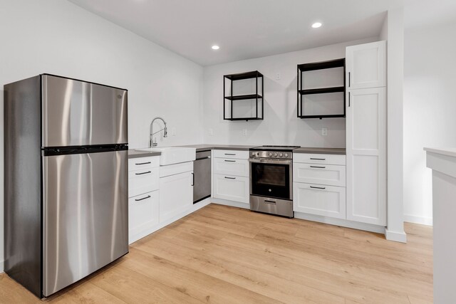 kitchen featuring appliances with stainless steel finishes, light hardwood / wood-style flooring, white cabinetry, and sink