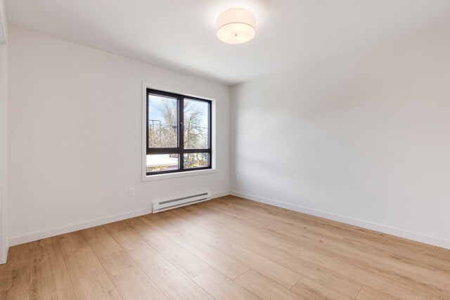 spare room featuring light hardwood / wood-style flooring and a baseboard heating unit