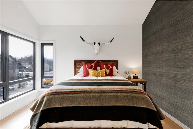 bedroom with multiple windows, hardwood / wood-style floors, and vaulted ceiling