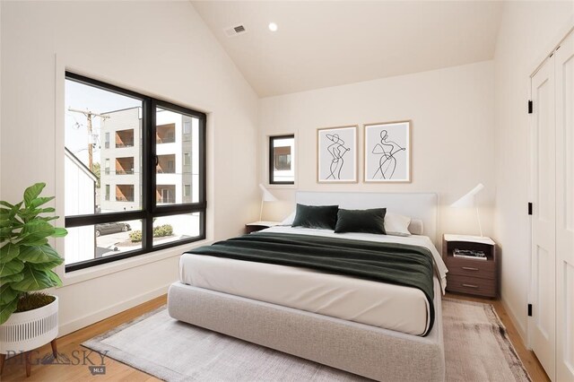 bedroom with vaulted ceiling, multiple windows, and light hardwood / wood-style floors