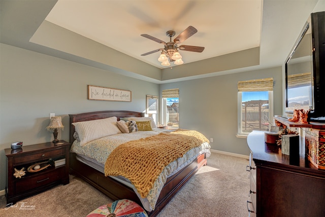 carpeted bedroom with a tray ceiling and ceiling fan