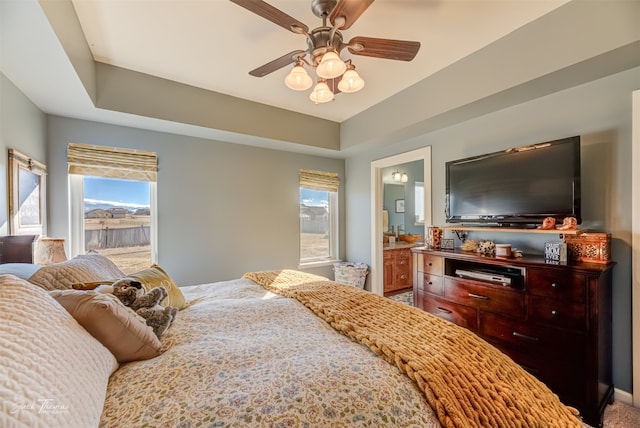 bedroom featuring connected bathroom, multiple windows, and ceiling fan